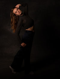 Young woman standing against black background
