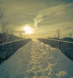 Snow covered land against sky during sunset