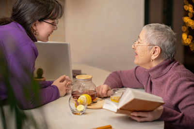 Side view of friends using digital tablet at home