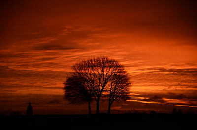 Silhouette bare tree on field against romantic sky at sunset