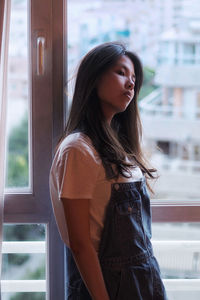 Portrait of young woman looking through window