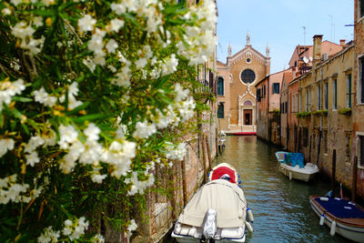 Boats moored on canal amidst buildings in city