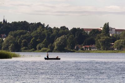 Man sitting on river against sky