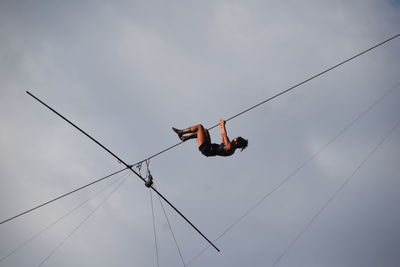 Low angle view of man skateboarding on rope against sky