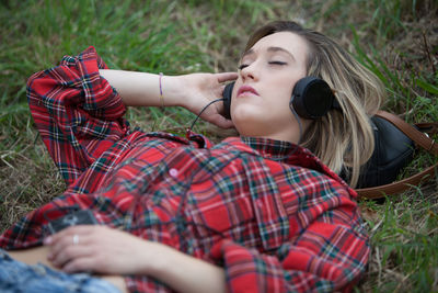 High angle view of woman listening music while lying on field