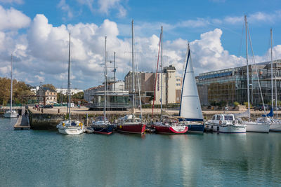 Sailboats moored in harbor against sky