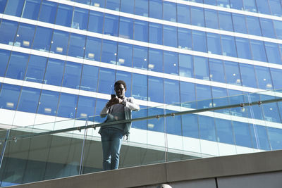Low angle view of person standing on glass building