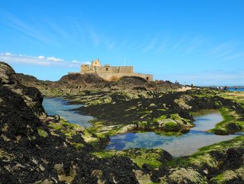 Castle by rocks against blue sky