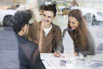 Happy couple signing document while meeting real estate agent in office