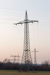 Low angle view of electricity pylon on field against sky