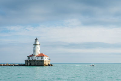 Lighthouse by sea against sky