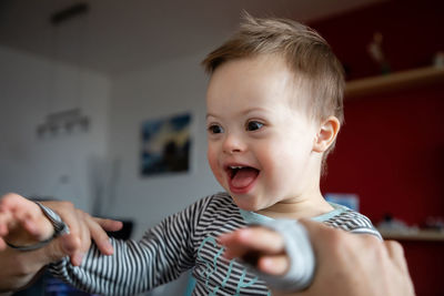 Happy boy with down syndrome held by father at home