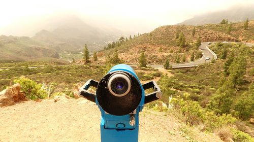 Coin-operated binoculars on mountain against sky