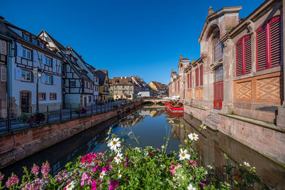 Canal amidst buildings against blue sky