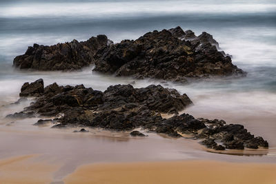 Rock formation on beach against sky