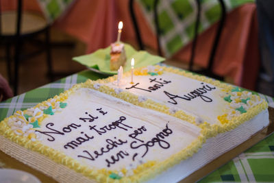Close-up of birthday cake with lit candles on table