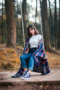 Portrait of woman sitting on swing at forest