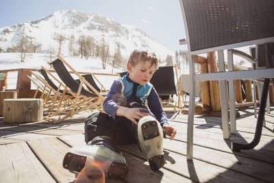 Boy wearing ski boots by seat on floorboard