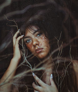 Close-up portrait of messy young woman by dead plants