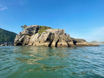 Rock formation in sea against clear blue sky