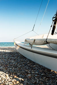 Sailboats moored on sea shore against clear sky