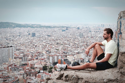 Full length of man looking at city buildings against sky