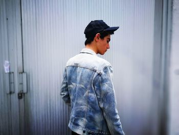 Teenage boy standing by corrugated iron