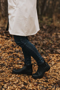 Low section of woman standing on autumn leaves