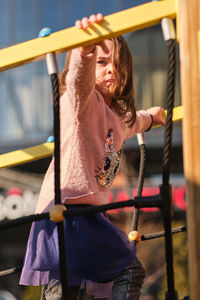 Full length of woman holding hands hanging in playground