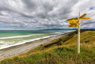 Information sign on beach against sky