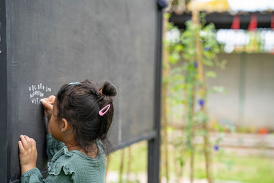 Portrait of cute girl writing alphabet on blackboard