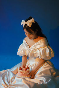 Woman looking away while sitting against blue sky