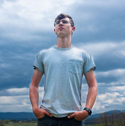 Young man looking away against sky