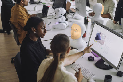 Multiracial female phd students discussing over computer in innovation lab