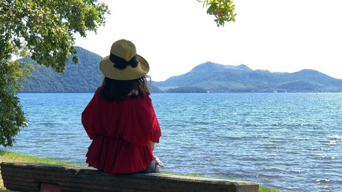 Rear view of woman standing by sea against sky