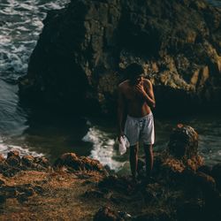 Shirtless man standing on rock