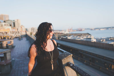 Woman standing by railing against sky