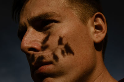 Close-up of young man standing against sky