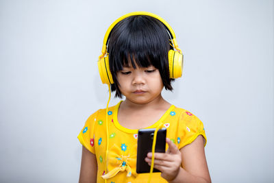 Happy boy using mobile phone against wall