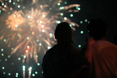 Low angle view of man and woman looking at firework display