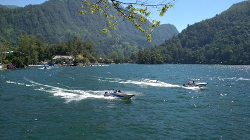 People on boat in sea against mountains