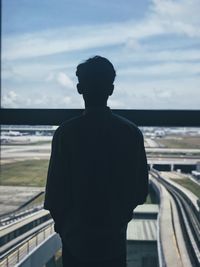 Rear view of man looking through window