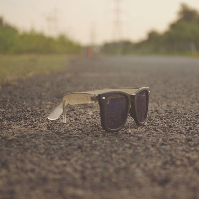 selective focus, surface level, focus on foreground, close-up, day, sand, grass, single object, road, outdoors, asphalt, street, field, no people, sunlight, still life, beach, nature, absence, tranquility