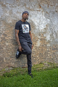 Full length portrait of young man standing against wall