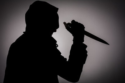 Low angle view of silhouette man holding camera against sky