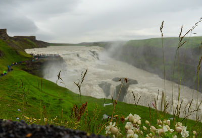 Scenic view of waterfall on field against sky