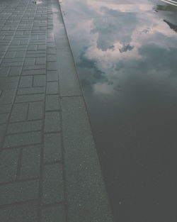 High angle view of wet footpath by lake against sky