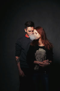 Portrait of happy man touching face against black background