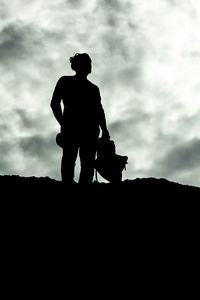 Low angle view of silhouette man sitting against sky