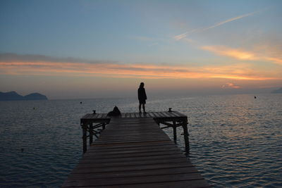 Silhouette man standing on pier by sea against sky during sunset